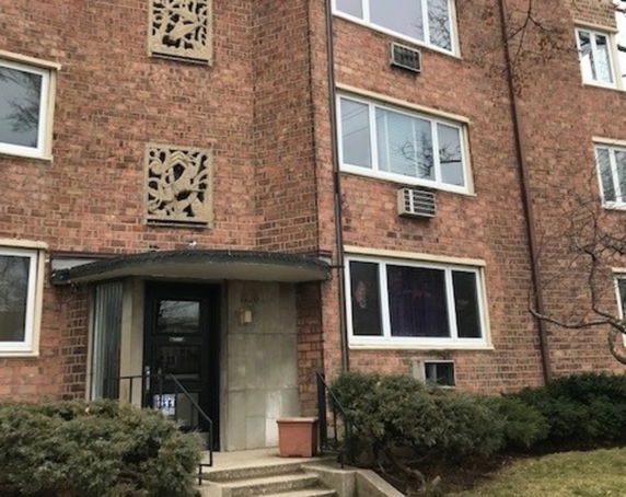 Front view of a multi-story brick apartment building with decorative wall elements and entrance steps.