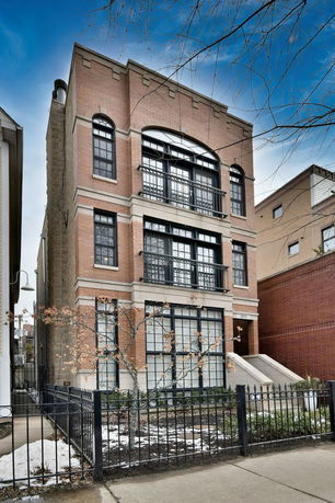 Front view of a multi-story brick building with large windows and a metal railing.