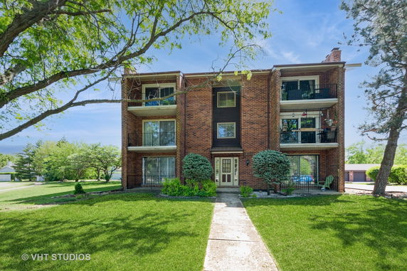 Front view of a three-story brick apartment building with balconies.