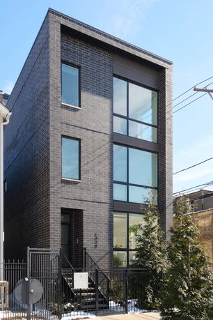 Front view of a modern three-story building with large windows and dark brick exterior.