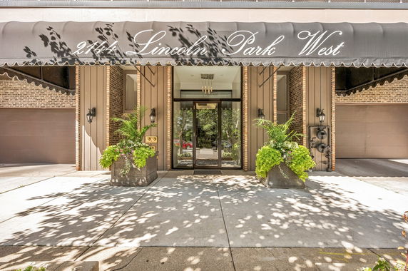 Front view of a building entrance with a large awning and two planters.