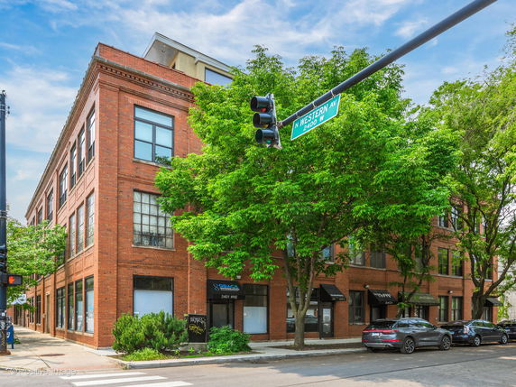 Front view of a three-story brick building on a street corner.