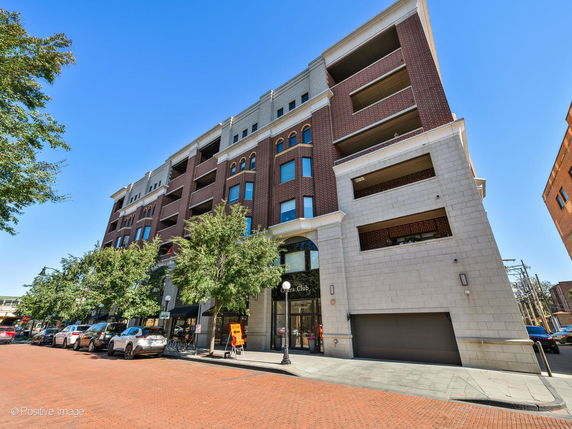 Front view of a multi-story brick building with retail space on the ground floor.