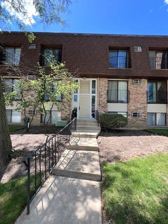 Front view of a multi-story residential building with brick exterior and large windows.