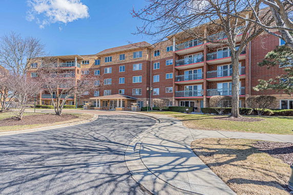 Front view of a multi-story brick apartment building with balconies.