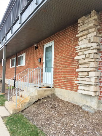 Front view of a building entrance with a brick exterior and a small set of steps.