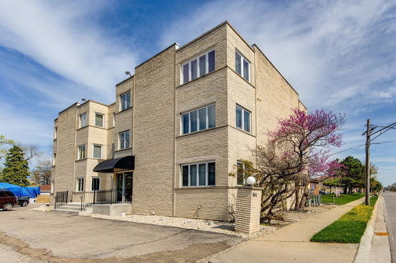 Front view of a multi-story brick building with large windows.