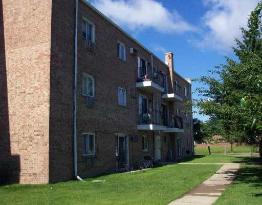 Side view of a multi-story brick apartment building with balconies.