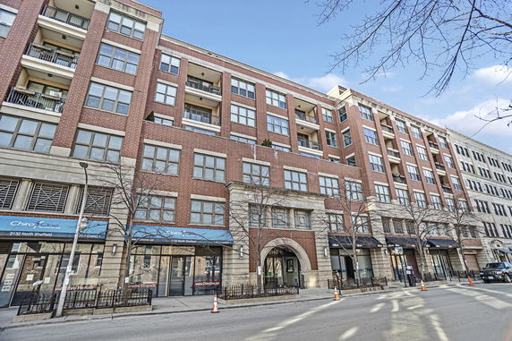 Front view of a multi-story brick building with retail space on the ground floor.