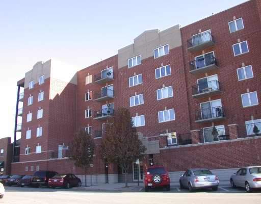 Front view of a multi-story apartment building with red brick exterior and balconies.