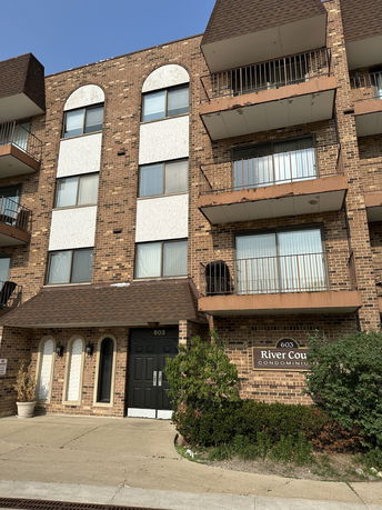 Front view of a multi-story condominium building with balconies and a central entrance.