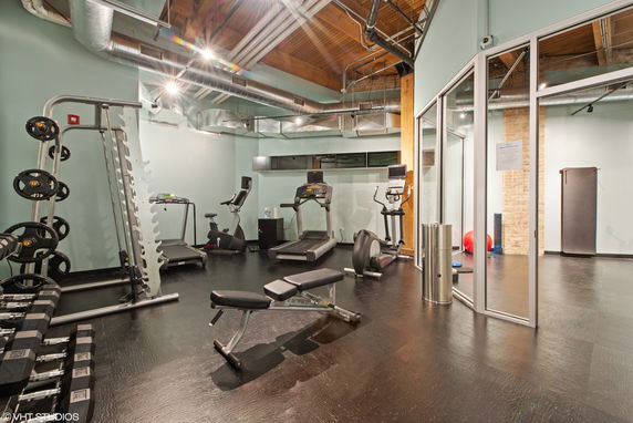 Indoor gym with exercise equipment including treadmills, weights, and stationary bikes.