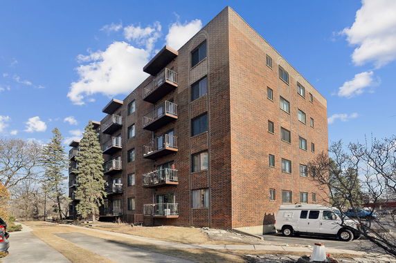 Front view of a multi-story brick apartment building with balconies.