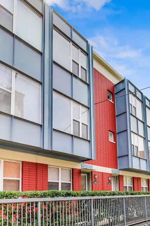 Front view of a modern multi-story building with large windows and metal siding.