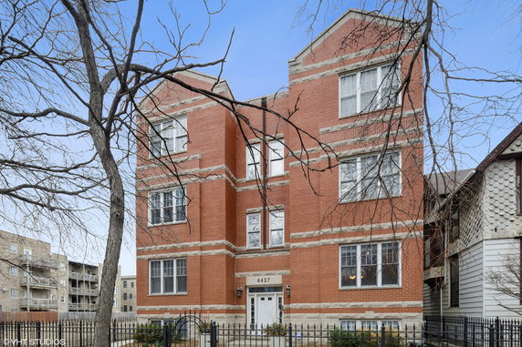 Front view of a multi-story brick apartment building with a white door.