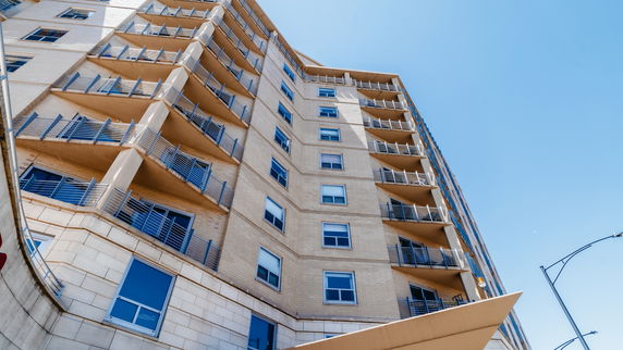 Front view of a multi-story building with balconies and blue windows.