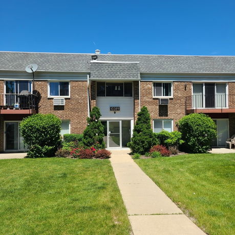 Front view of a two-story brick apartment building with balconies.