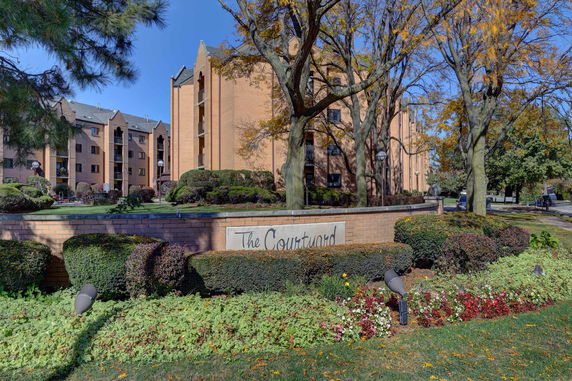 Front view of a multi-story brick apartment building with landscaped surroundings.