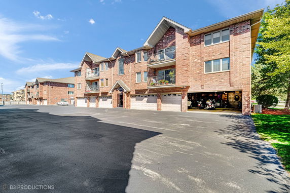 Front view of a multi-story brick residential building with garages.