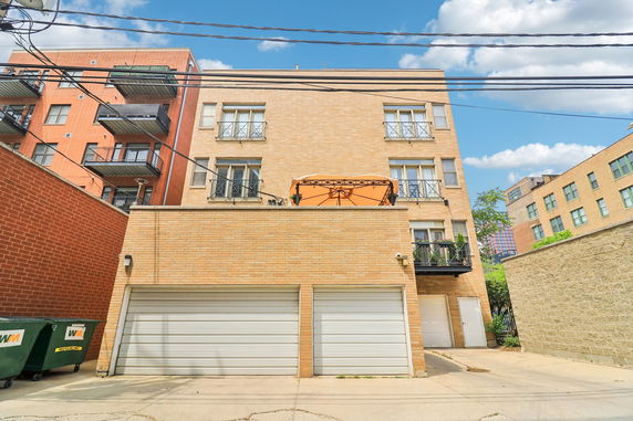 Front view of a multi-story brick building with balconies and garage doors.