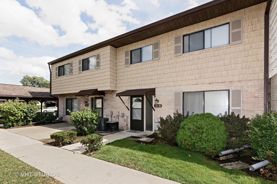 Front view of a two-story residential building with beige siding and brown trim.