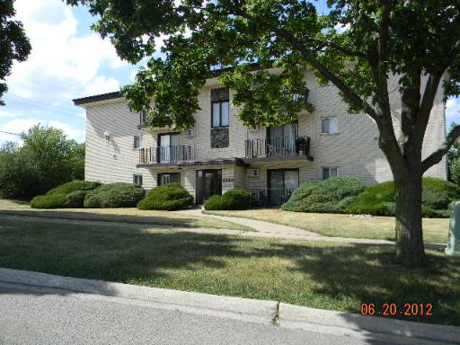 Front view of a two-story building with balconies and surrounding greenery.