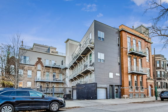 Front view of a multi-story building with balconies and a mix of brick and siding exterior.