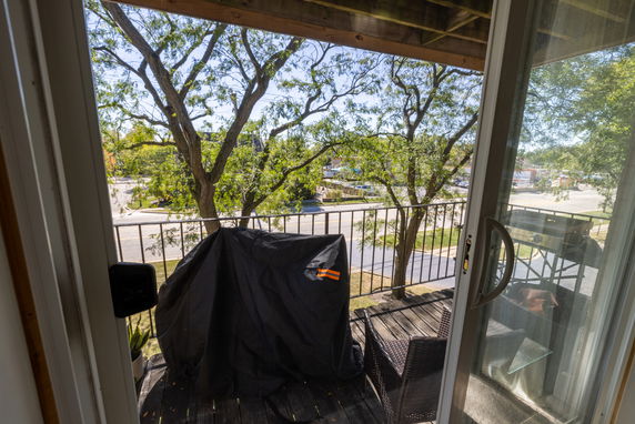 View from a balcony showing a street and trees outside.