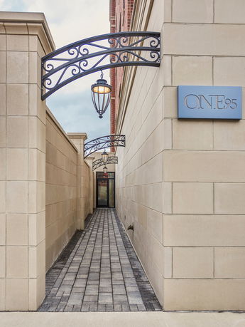 Front view of a building with a pathway adorned with black metal lanterns and a wall sign.