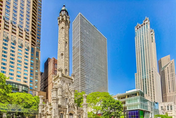 Front view of a historic building with a tall tower alongside modern skyscrapers.