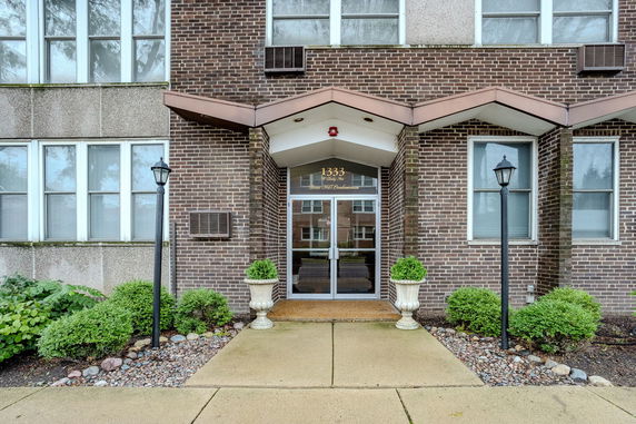 Front entrance of a brick condominium building with glass doors.