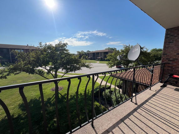 Balcony view of surrounding residential area with buildings and trees.