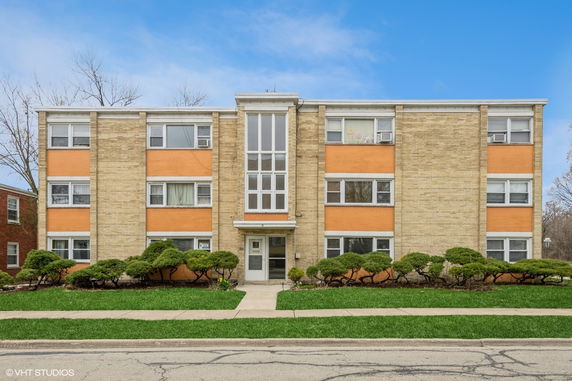 Front view of a three-story apartment building with a central entrance and mixed brickwork facade.