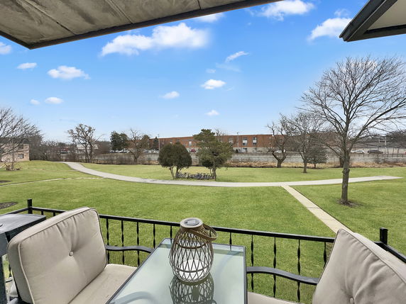 Panoramic view from a balcony overlooking a grassy yard and distant buildings.