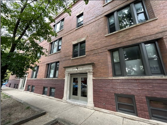 Front view of a multi-story brick building with large windows and an entrance.