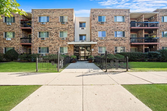 Front view of a multi-story brick apartment building with balconies and multiple windows.