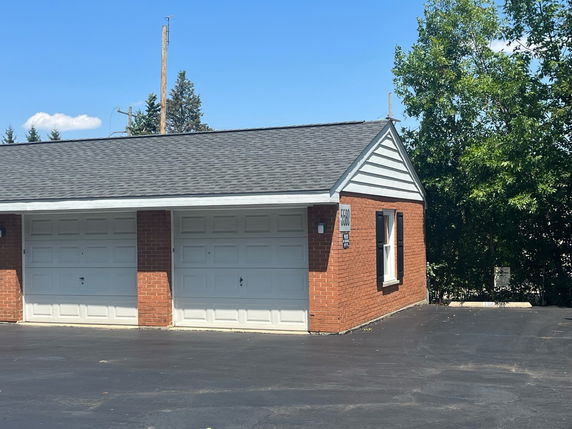 Front view of a brick building with attached garage and gable roof.