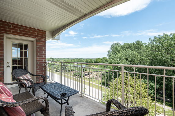Balcony view from a building overlooking greenery and distant landscapes.