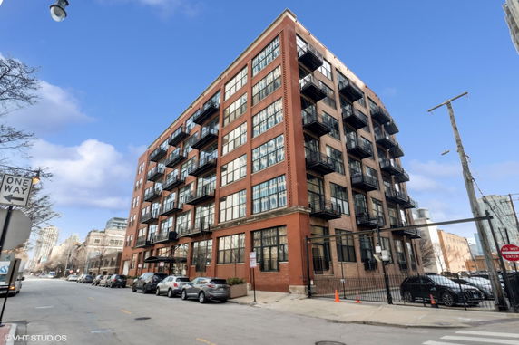 Front view of a multi-story brick apartment building with balconies.