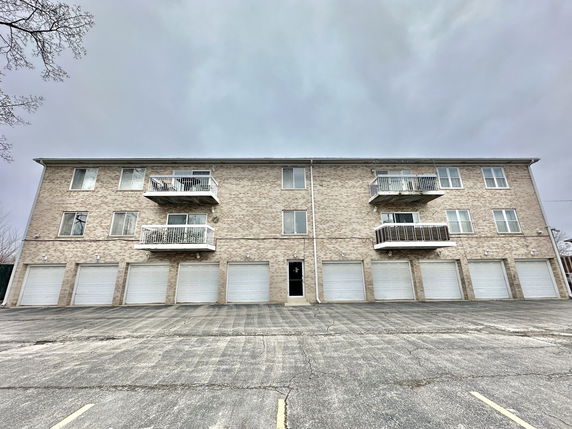 Front view of a three-story building with multiple garage doors and balconies.