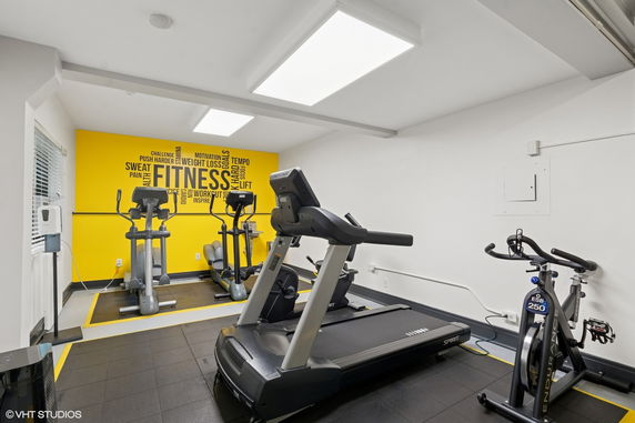 Indoor gym with exercise equipment including a treadmill, exercise bike, and elliptical machine.