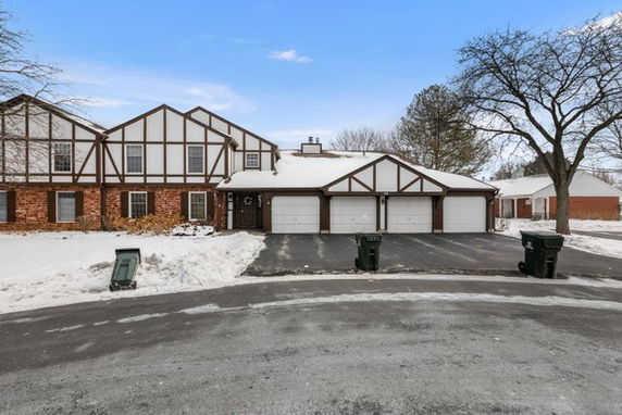 Front view of a two-story house with a triple garage covered in snow.