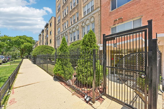 Front view of a multi-story apartment building with a gated entrance.