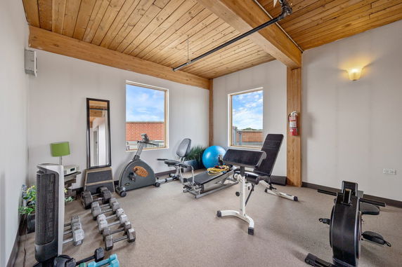 Indoor gym area with exercise equipment and wooden ceiling.