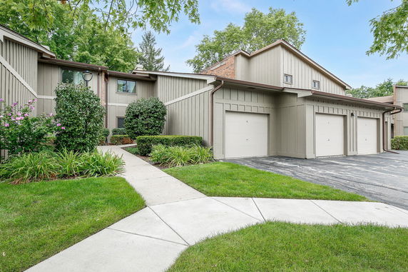 Front view of a two-story building with garages and a pathway.
