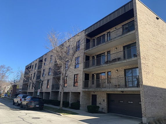 Front view of a multi-story apartment building with balconies and brick exterior.
