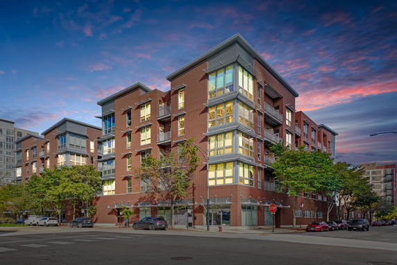 Front view of a multi-story apartment building with brick exterior and large windows.