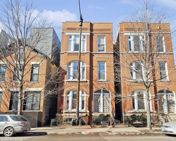 Front view of a three-story brick building with arched windows and a front entrance.