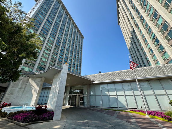 Front view of a tall building with large glass windows and a flagpole.