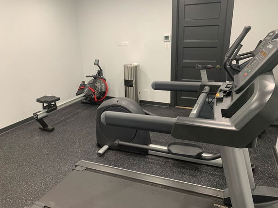 Indoor gym area with exercise equipment including a treadmill and rowing machine.